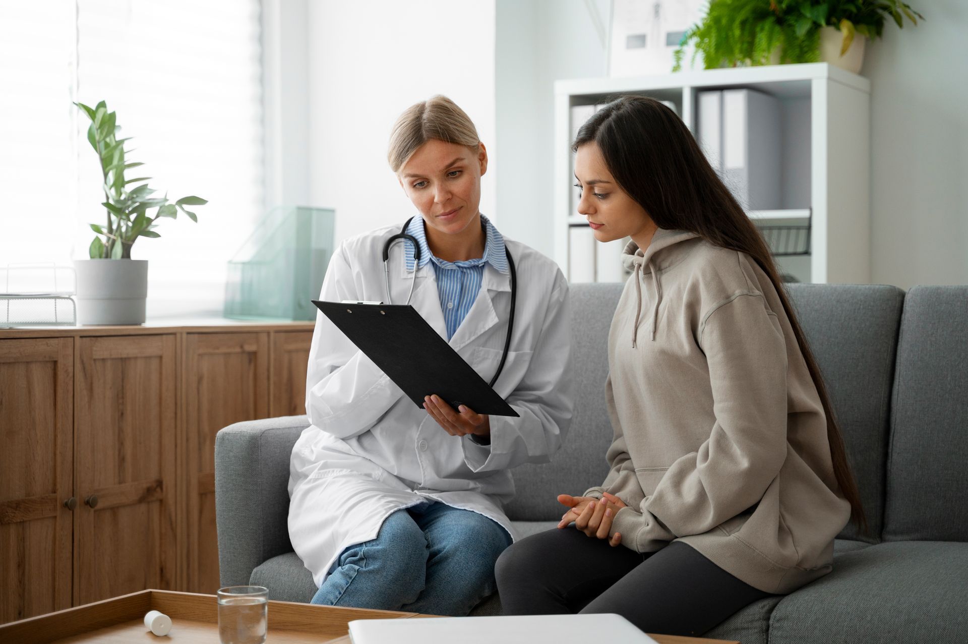 Doctor showing a tablet to a seated patient in a bright living room