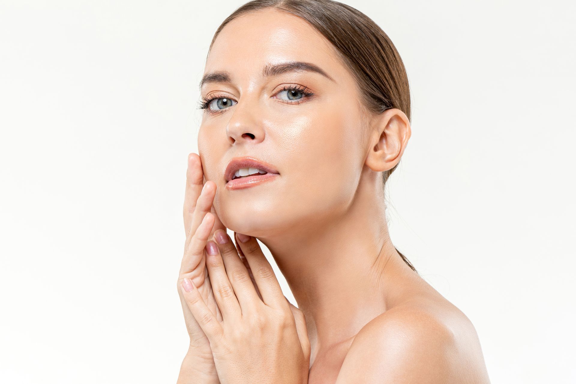 Woman gently touching her cheek against a white background