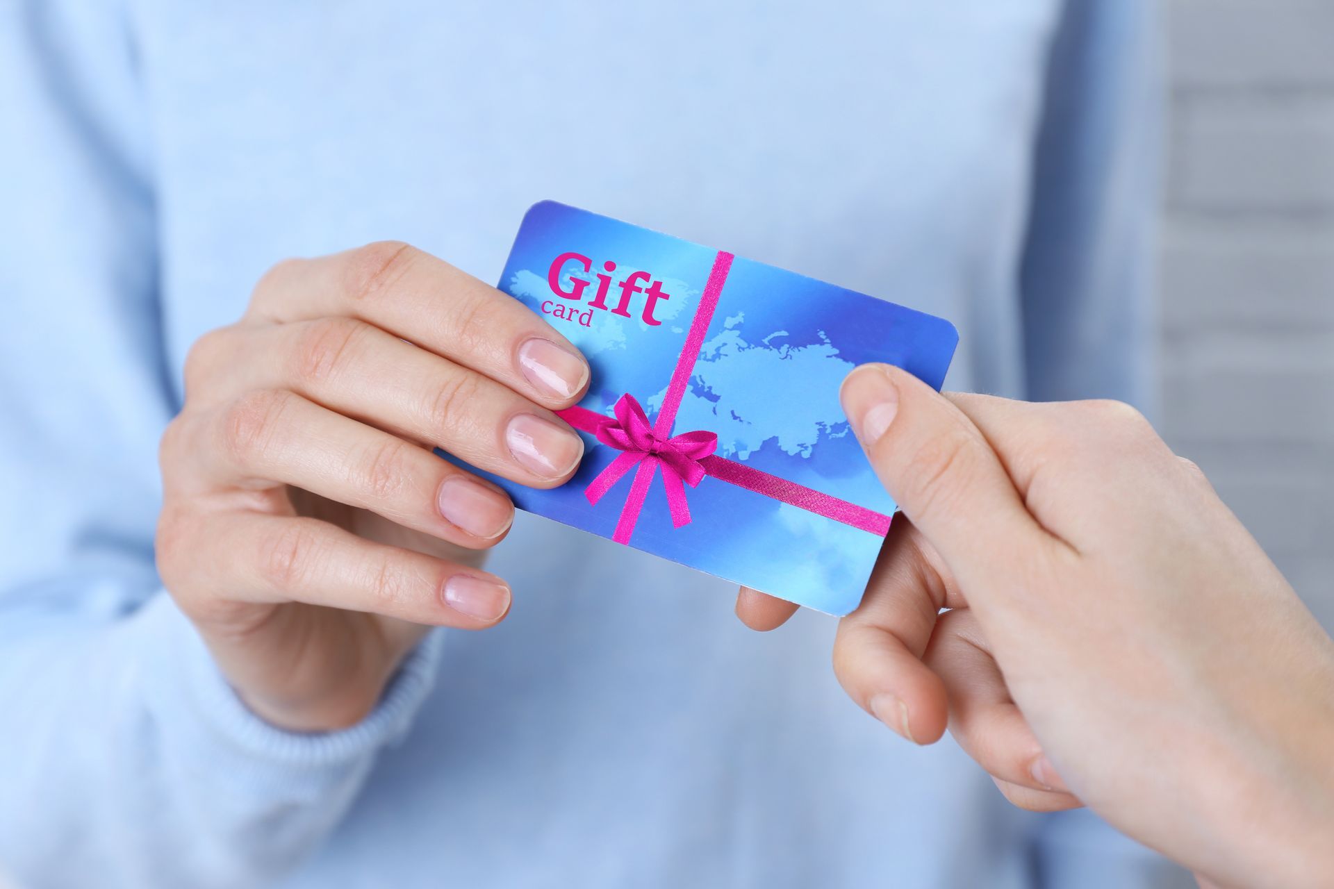 A person is giving a gift card to another person.