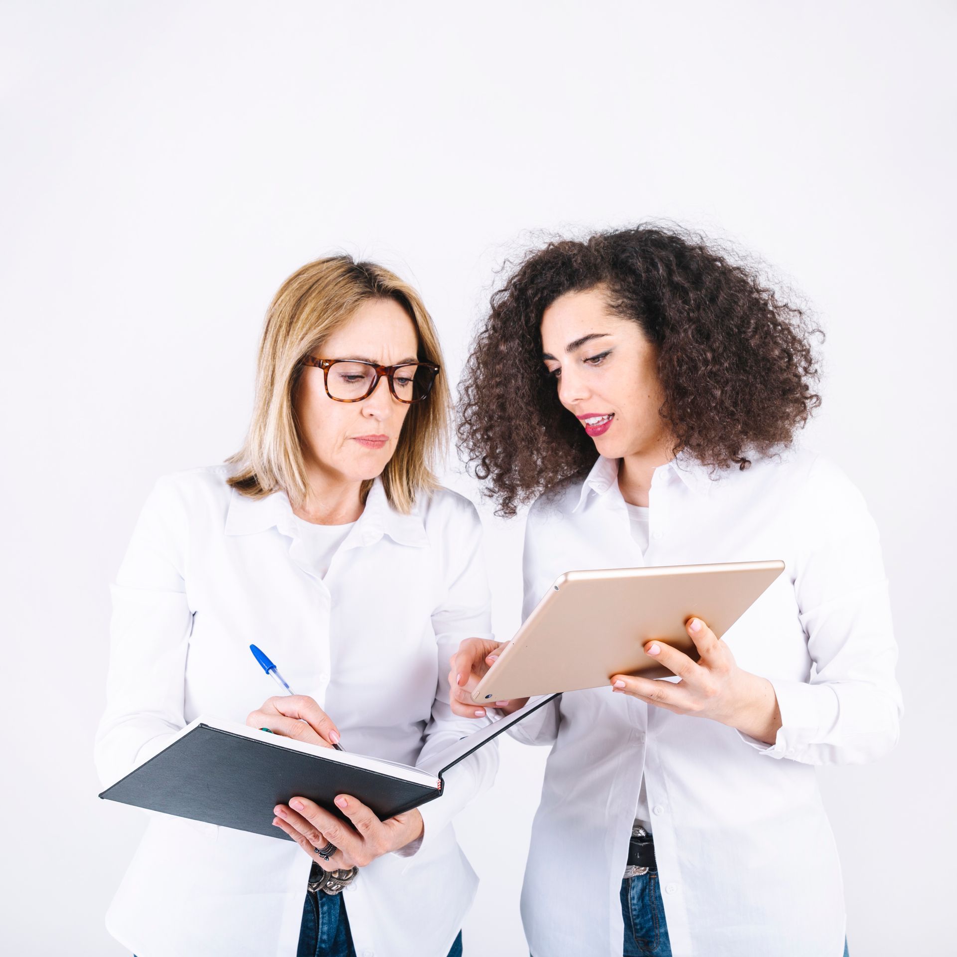 Two people in white lab coats reviewing notes and a tablet against a white background