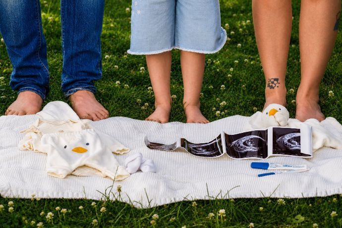 Bare feet and a white blanket on grass with several black-and-white printed items laid out