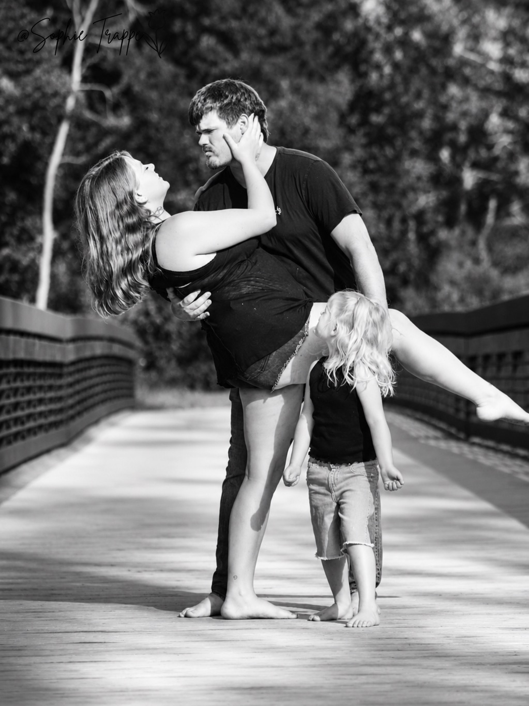 Three people taking a photo on a bridge.