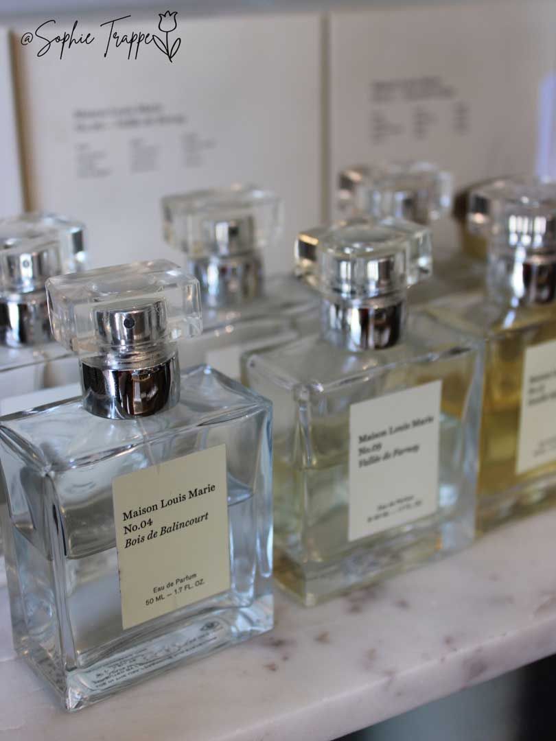 Clear glass perfume bottles on a marble counter with labels and silver caps.