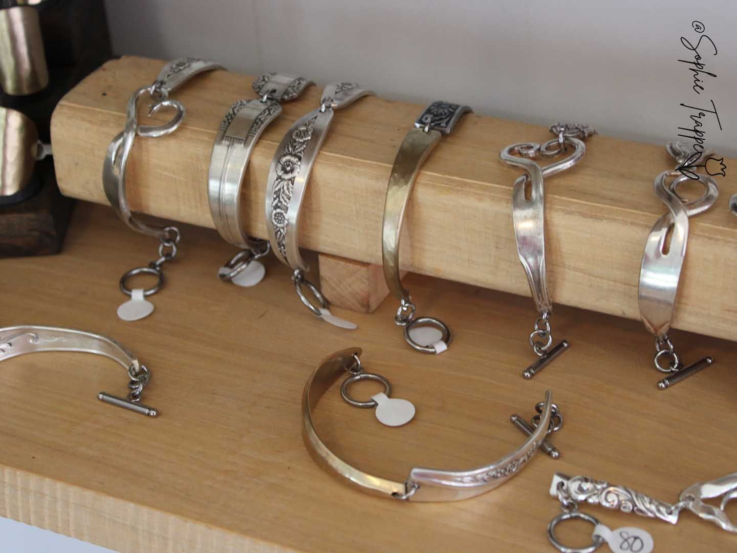 Silver bracelets displayed on a wooden stand and tabletop in a jewelry shop