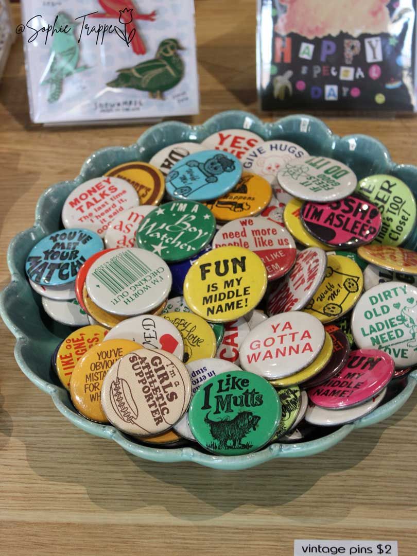 A bowl filled with colorful round pins with motivational phrases on a table.