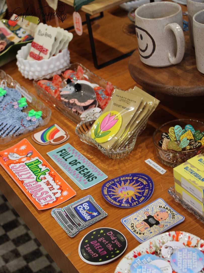 Assorted colorful stickers and small packaged items displayed on a wooden table with a white mug nearby