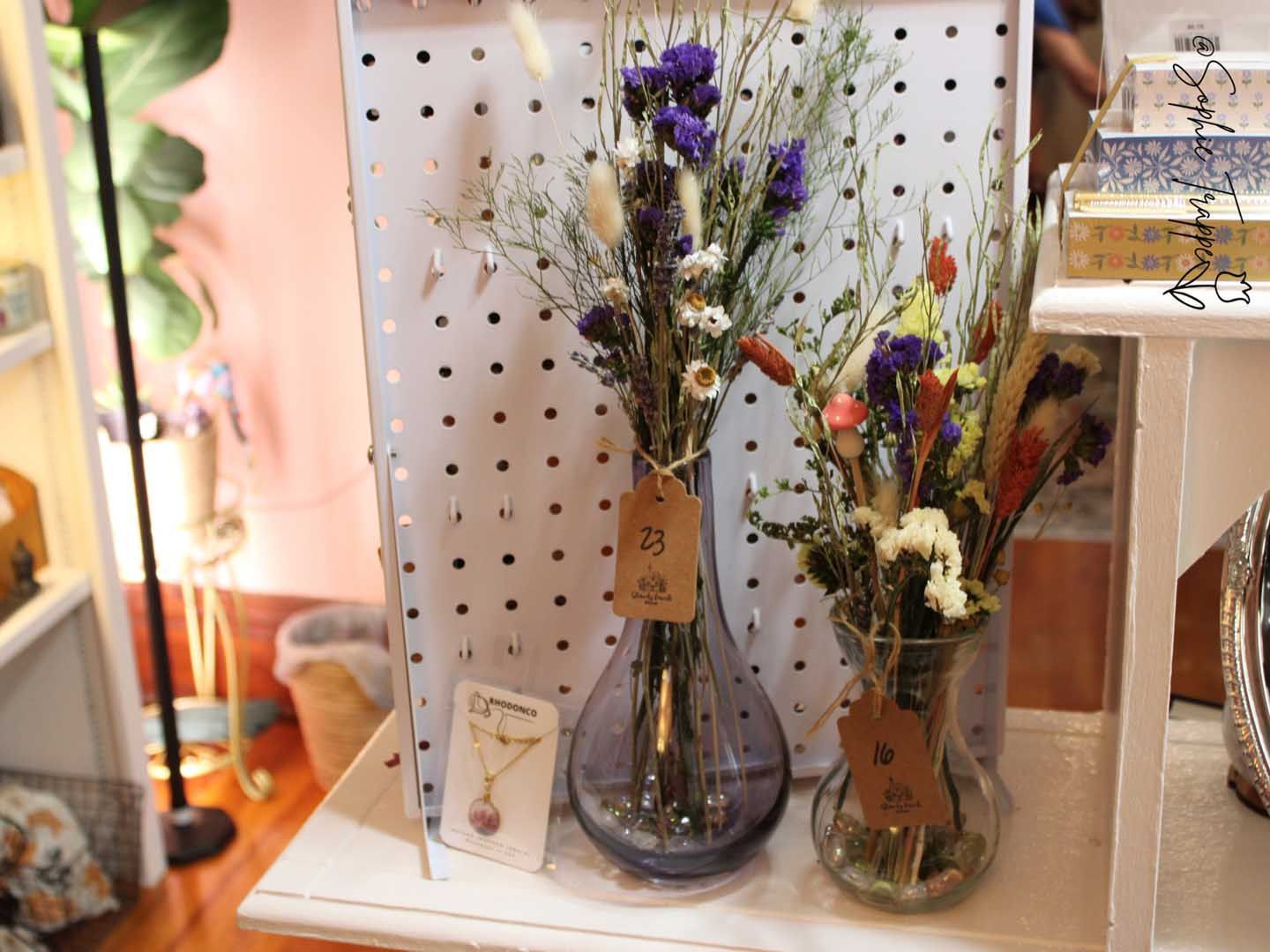 Vases of dried flowers on a pegboard shelf in a softly lit shop display
