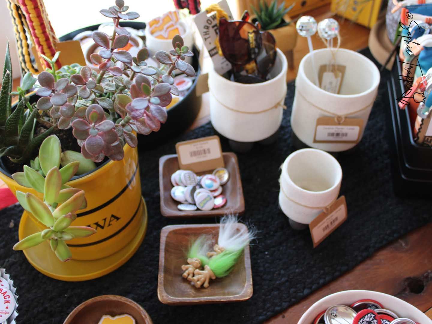 Assorted potted succulents and small display items arranged on a table at a plant market