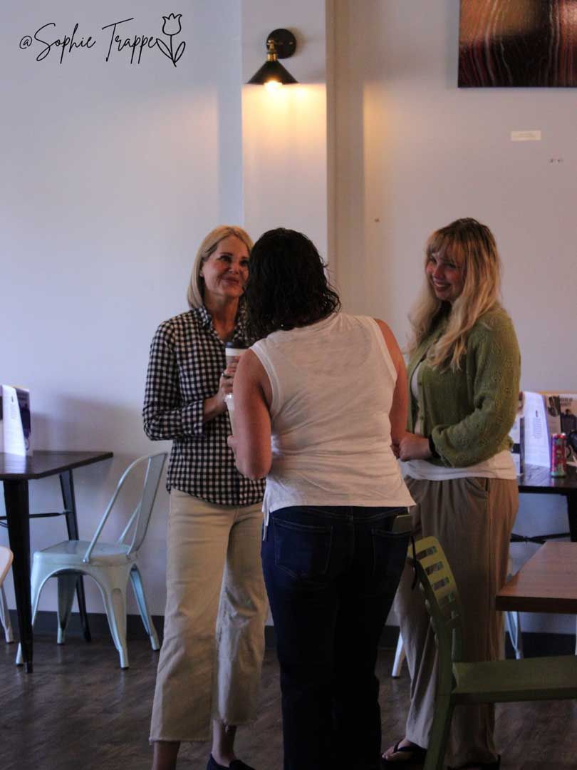 Three people chatting in a bright room near a table and chairs