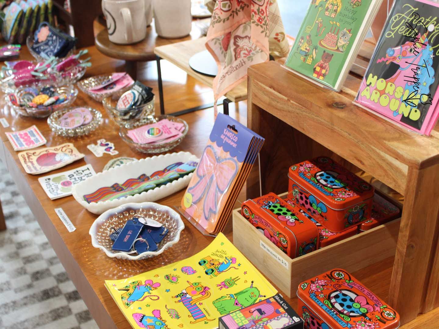 Colorful handmade crafts and jewelry displayed on a wooden table and shelves in a shop