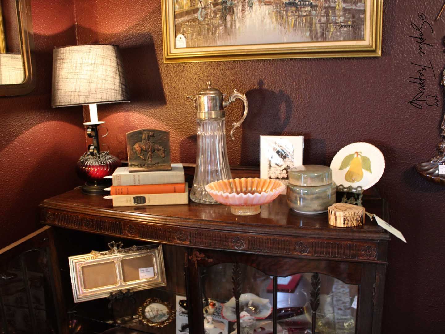 Decorated sideboard with lamp, framed art, glassware, and candles in a warmly lit room