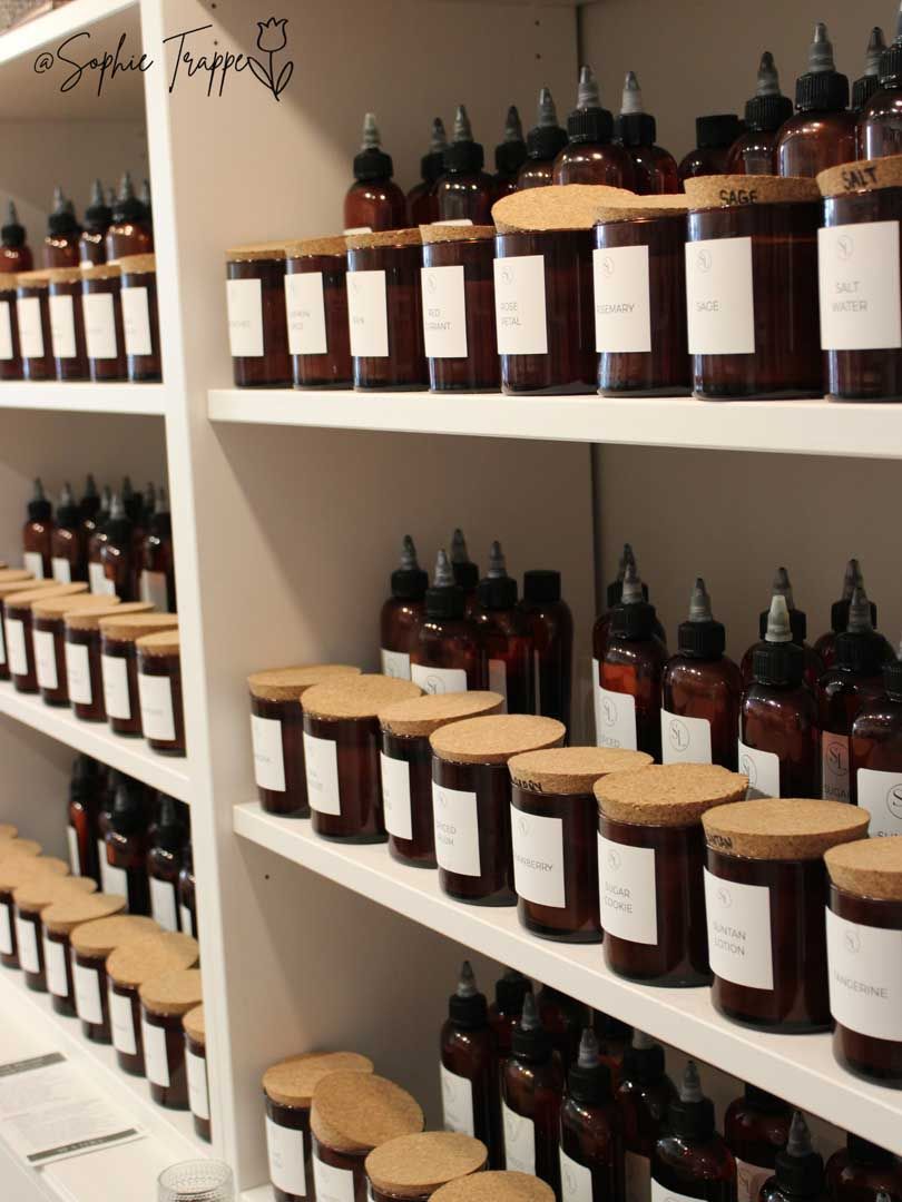 Shelves of dark glass jars with beige lids in a white retail display