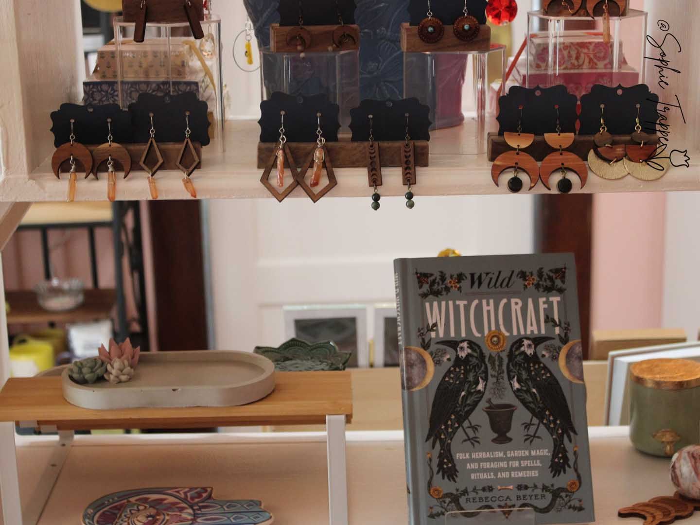A tabletop display with jewelry and a witchcraft-themed book in a bright shop interior