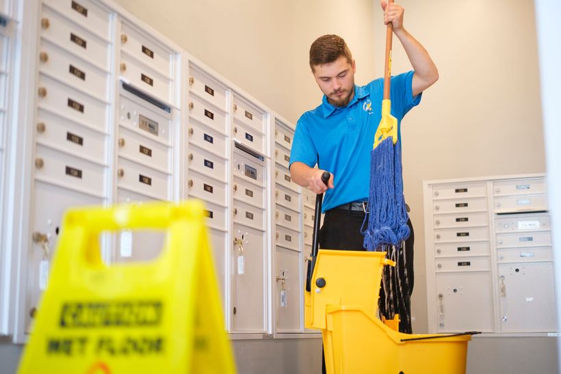 Custodian mopping near mailboxes with