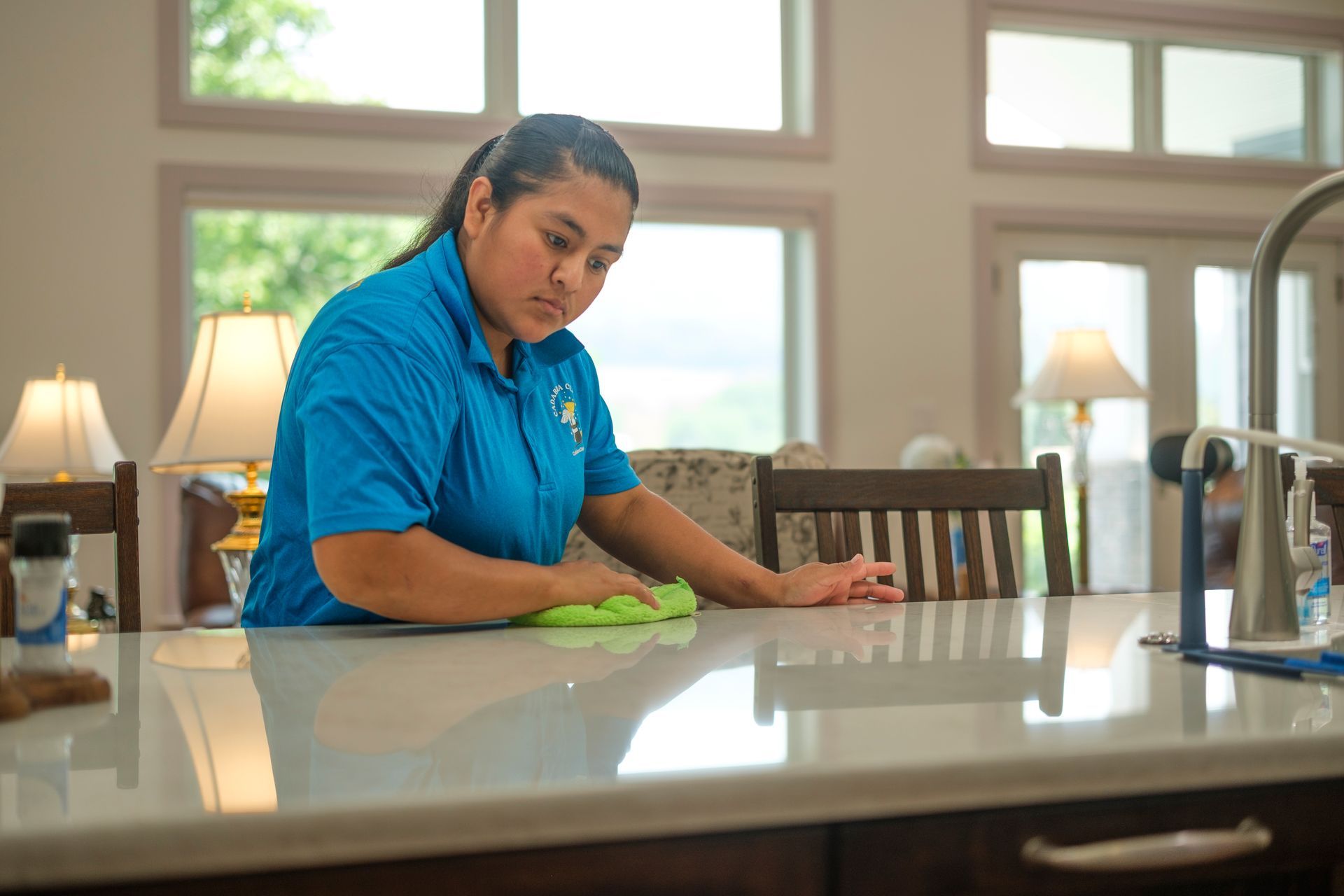 Person cleaning a white countertop in a bright kitchen.