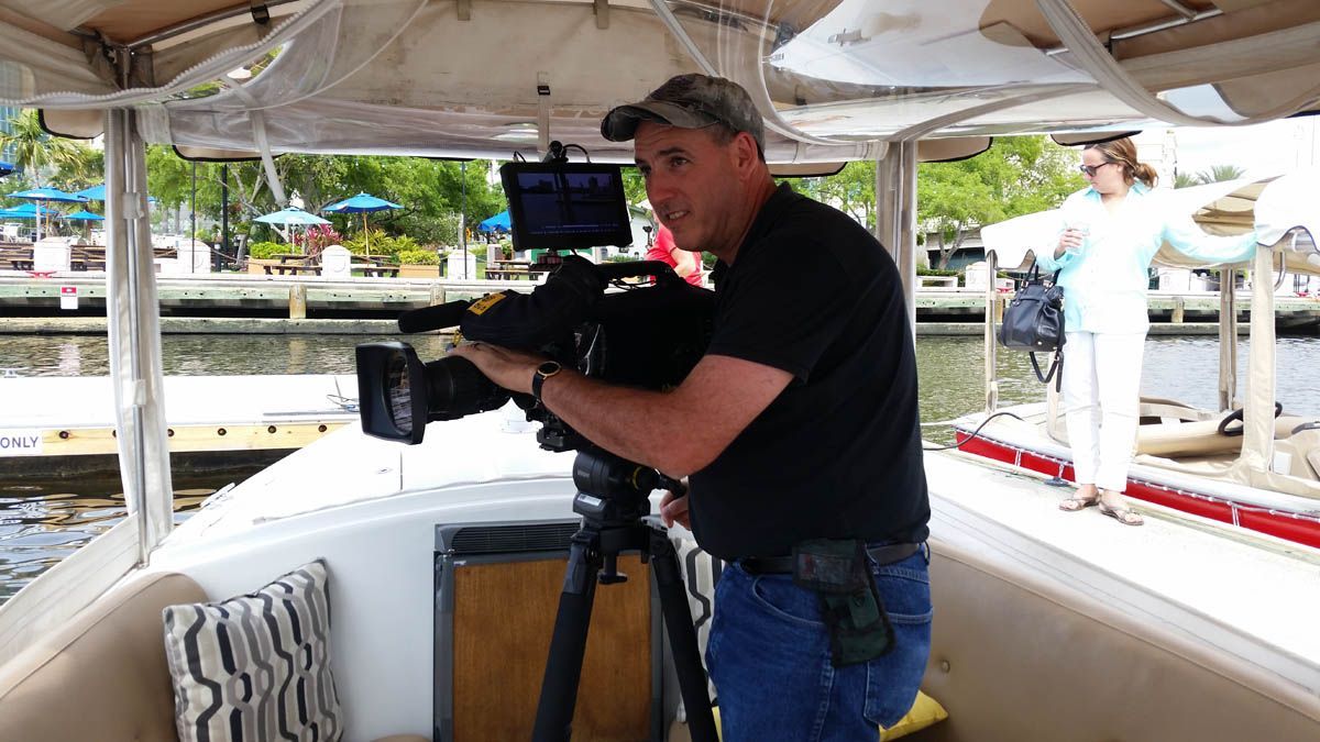 A man is standing on a boat holding a camera.