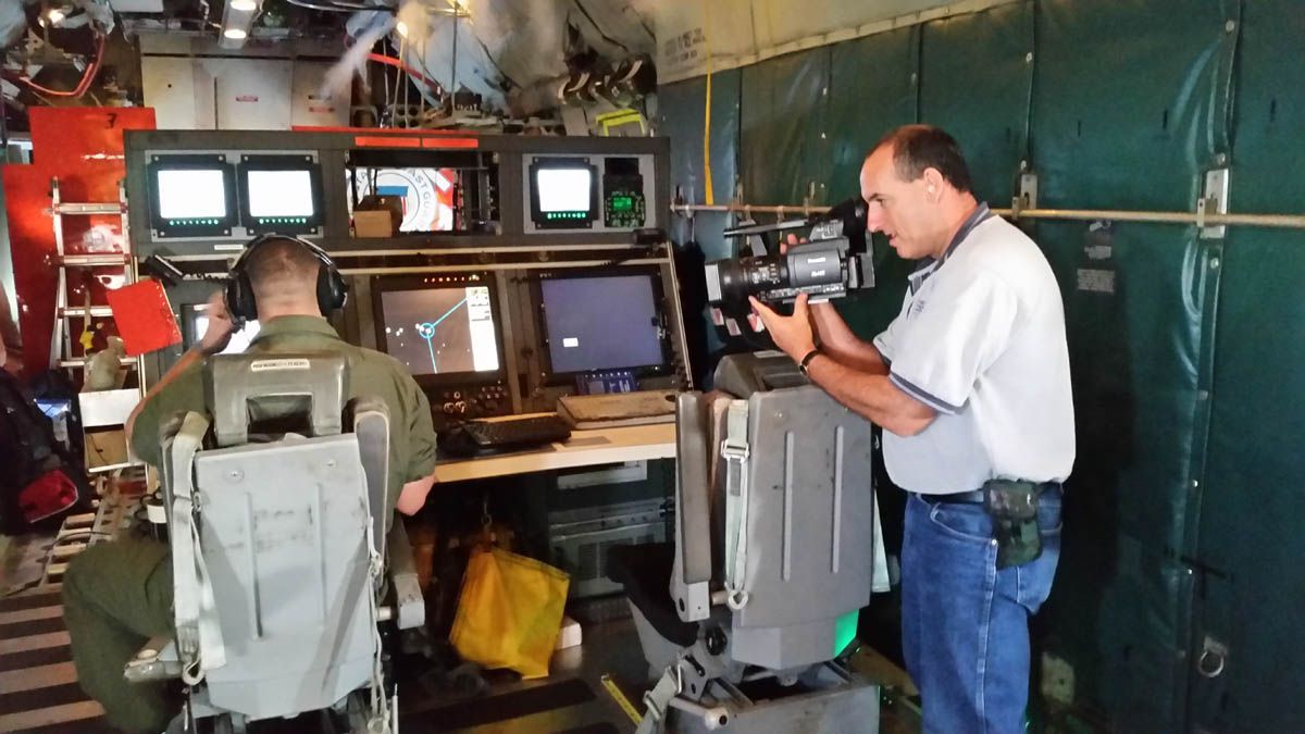 A man in a wheelchair is talking to another man while holding a camera
