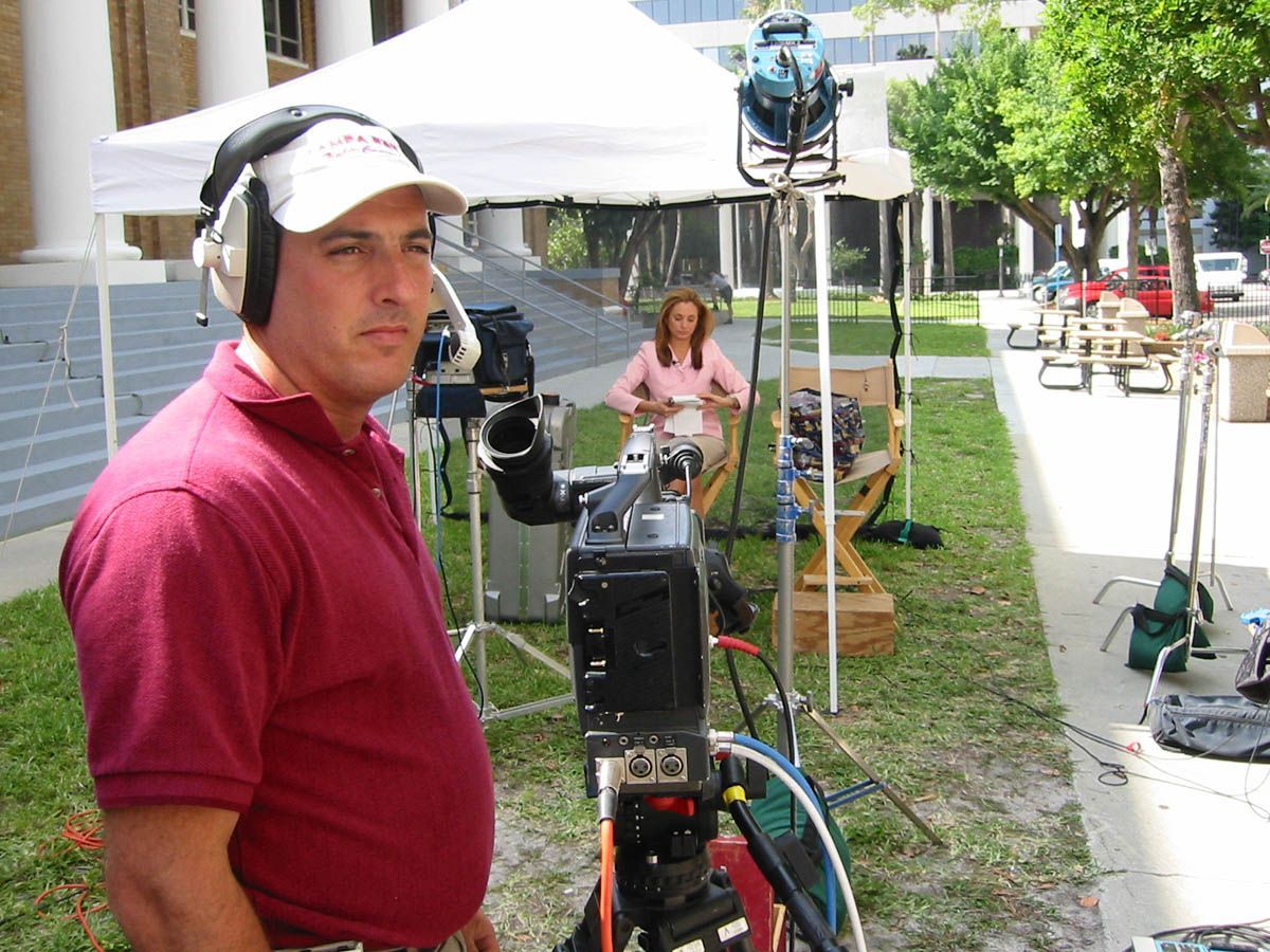 A man wearing headphones stands in front of a camera