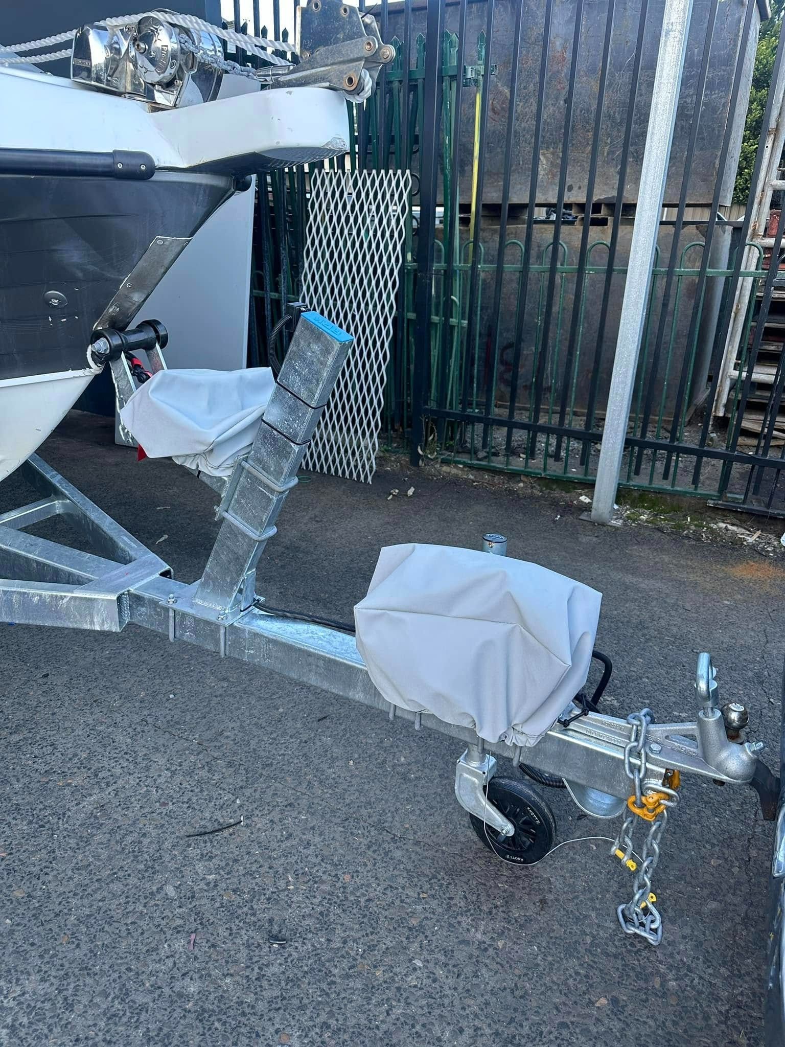 A Boat Is Sitting on A Trailer Next to A Fence — Don's Marine Repairs in Woy Woy, NSW