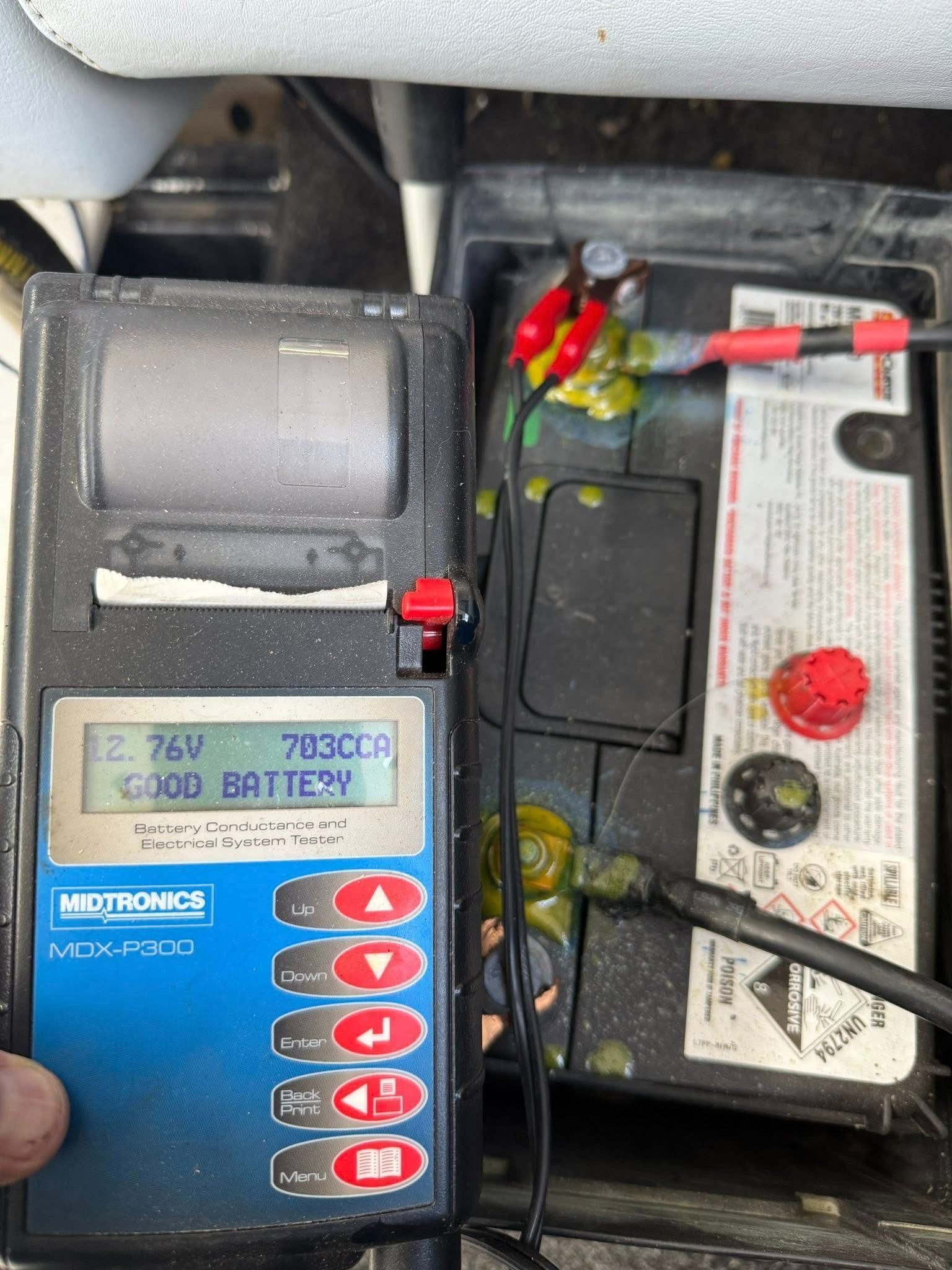 A Person Is Holding a Tester Next to A Car Battery — Don's Marine Repairs in Ettalong, NSW
