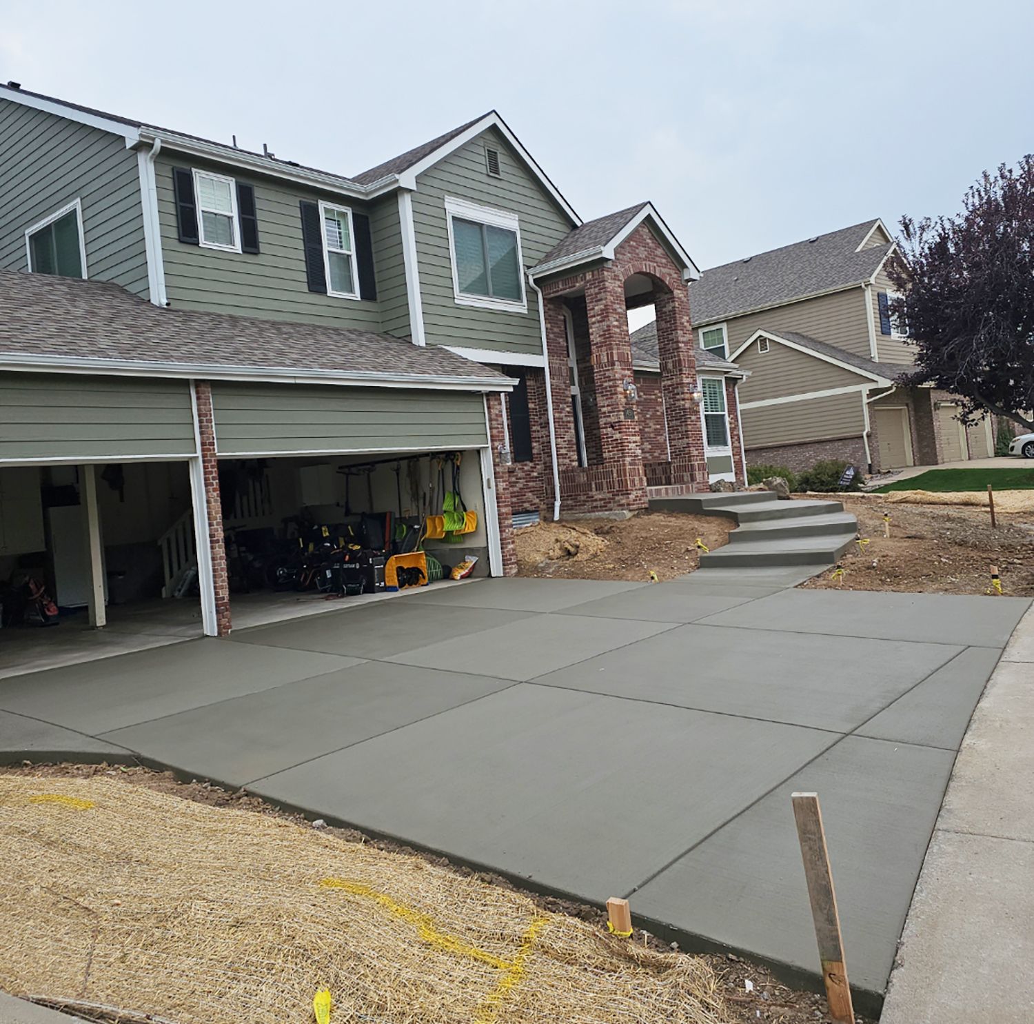Suburban two-story house with a fresh concrete driveway and open garage door