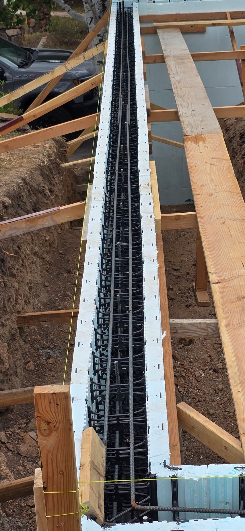 Wooden roof framing with a long white insulated channel and black wiring running through the center