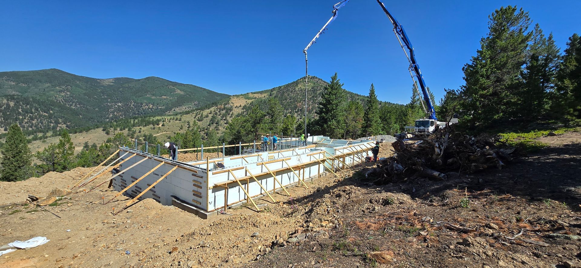 Solar panels on a raised frame at a mountainside construction site under a clear blue sky