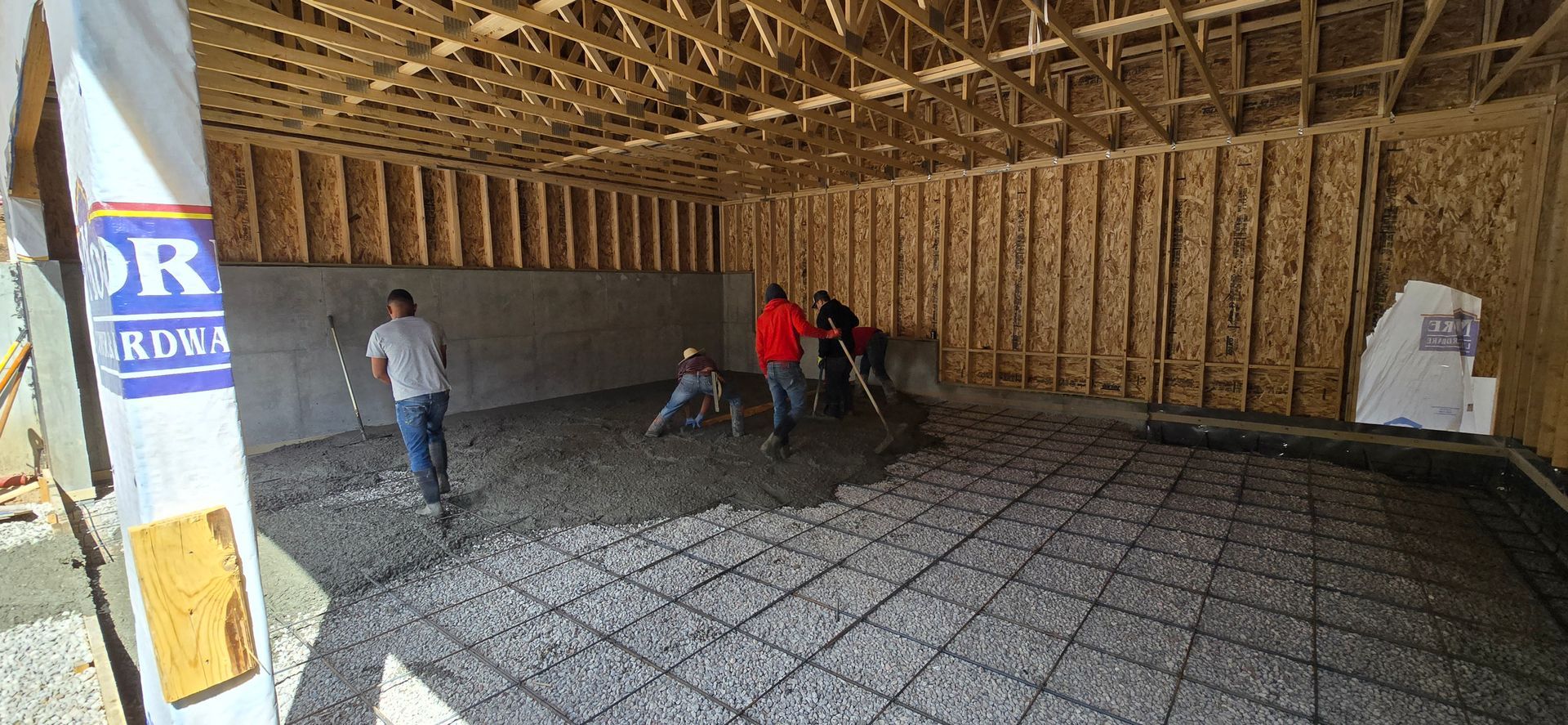 Workers installing floor reinforcement in a framed house interior