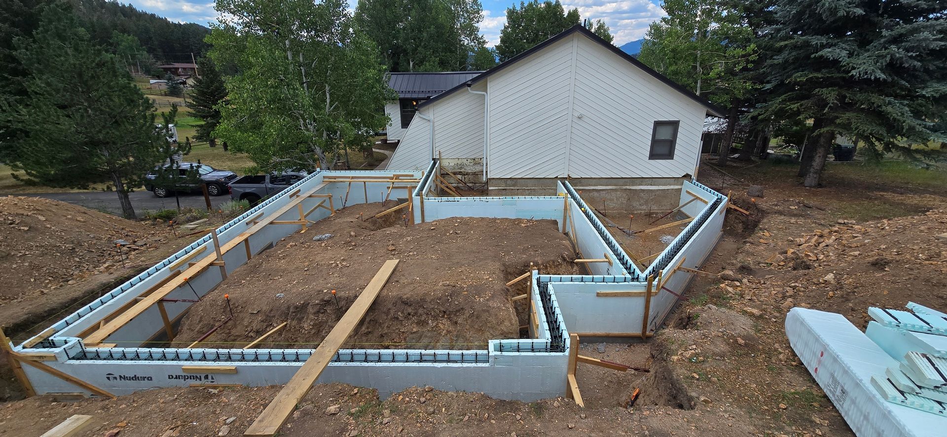 Foundation forms and lumber for a house under construction in a wooded lot