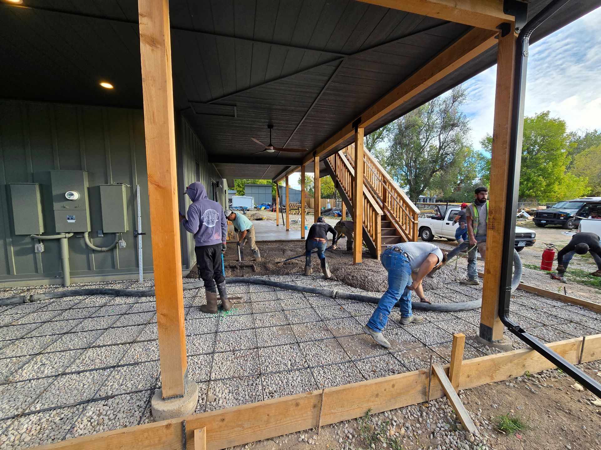 Workers pouring gravel under a covered wooden structure on a construction site