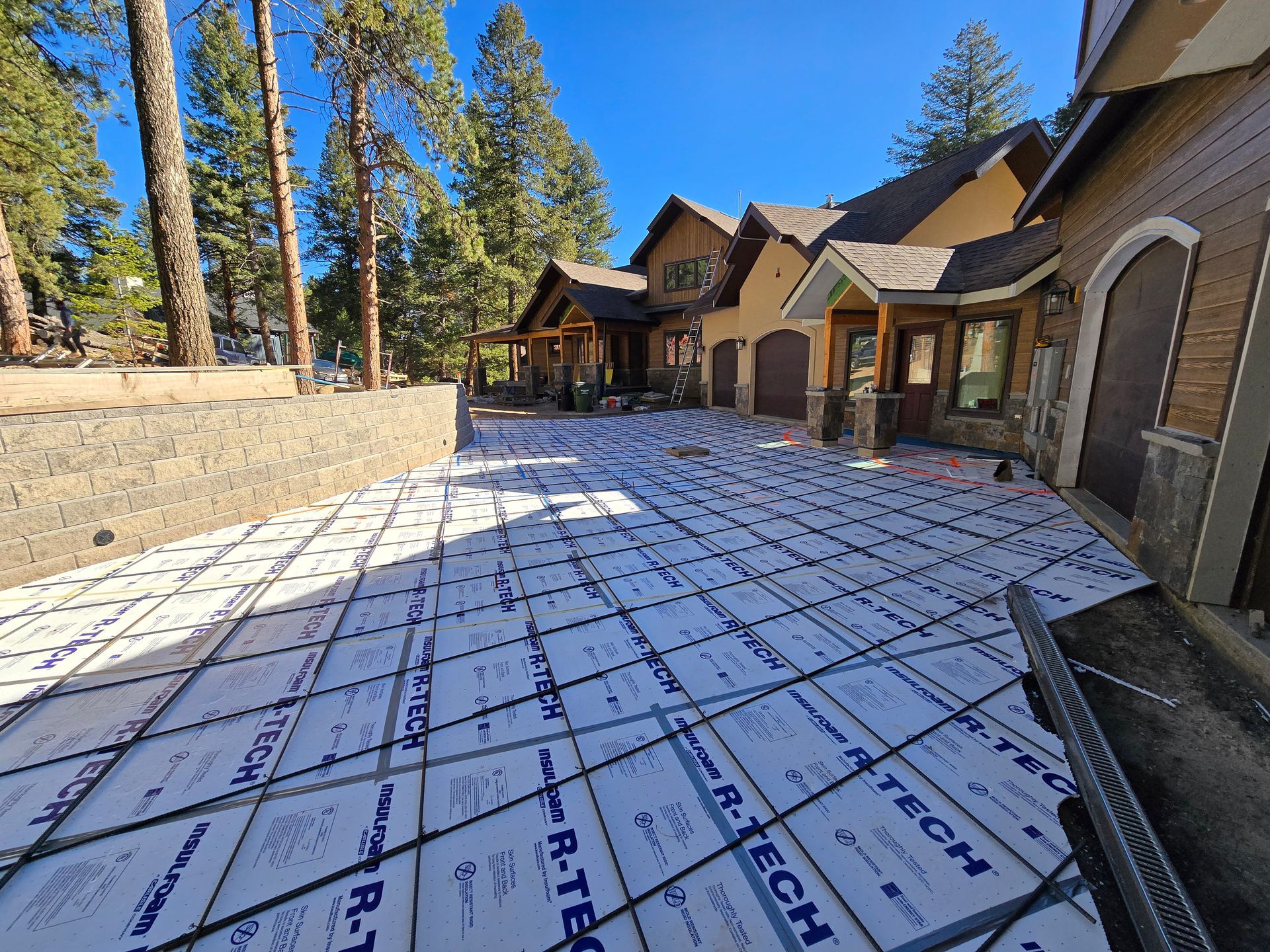 Roof underlayment on a house under construction, with tan walls, trees, and blue sky in the background