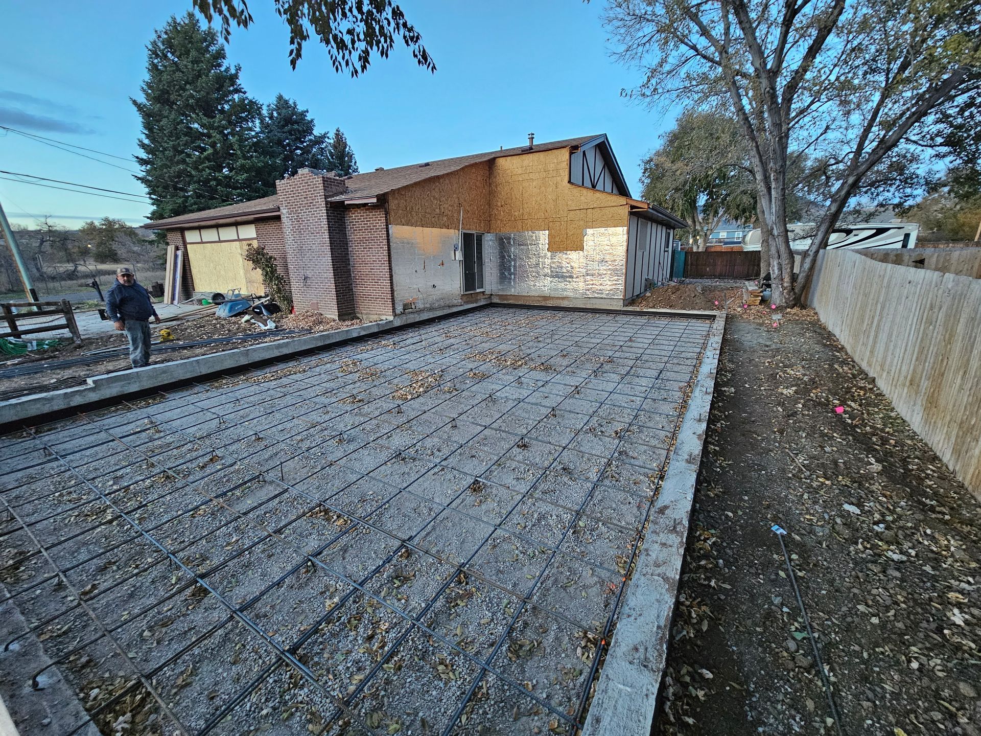 Backyard under construction with a roof deck, plywood house, and fenced yard on a clear day