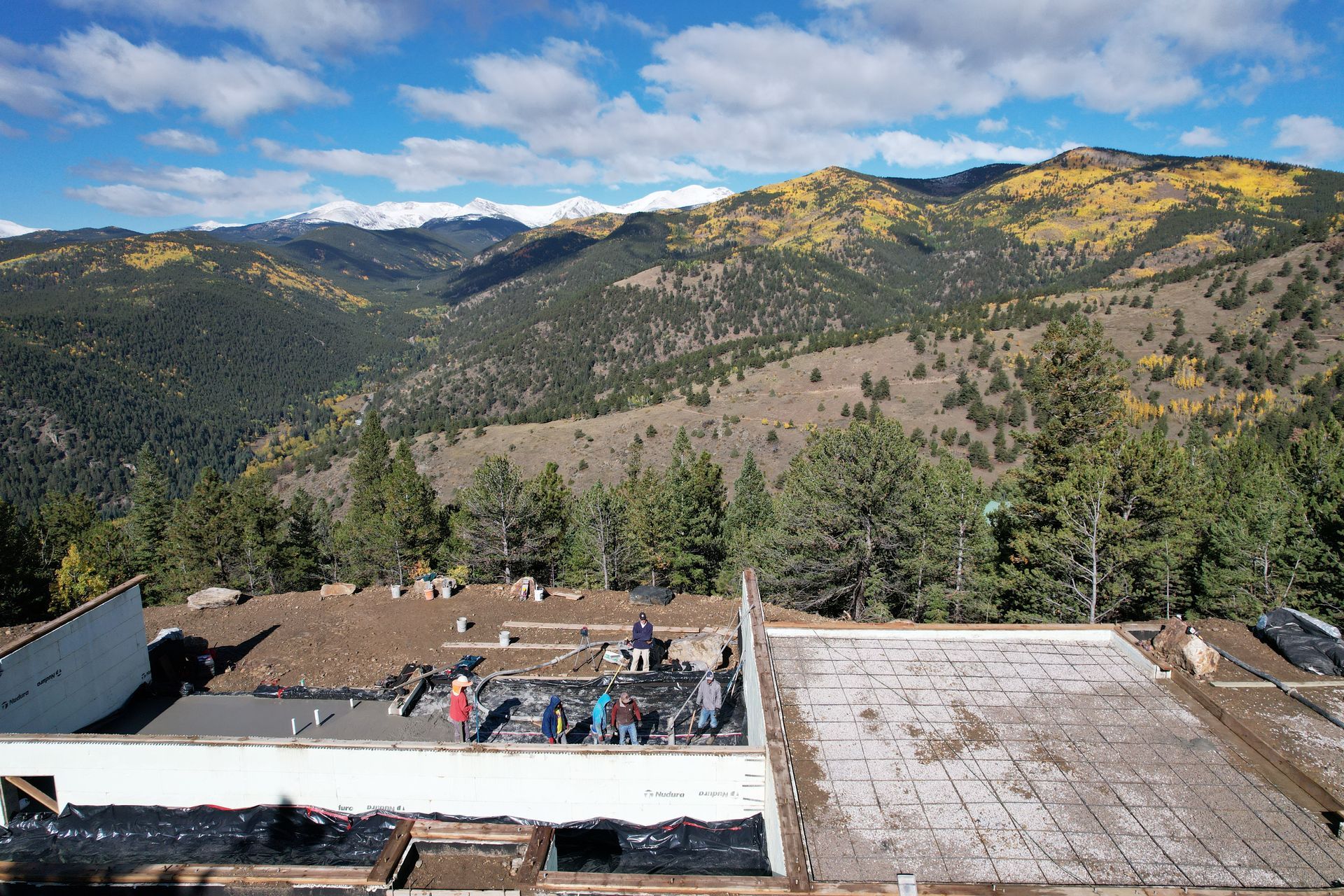 Mountain overlook with evergreen forest, autumn hills, and a stone terrace under a blue sky