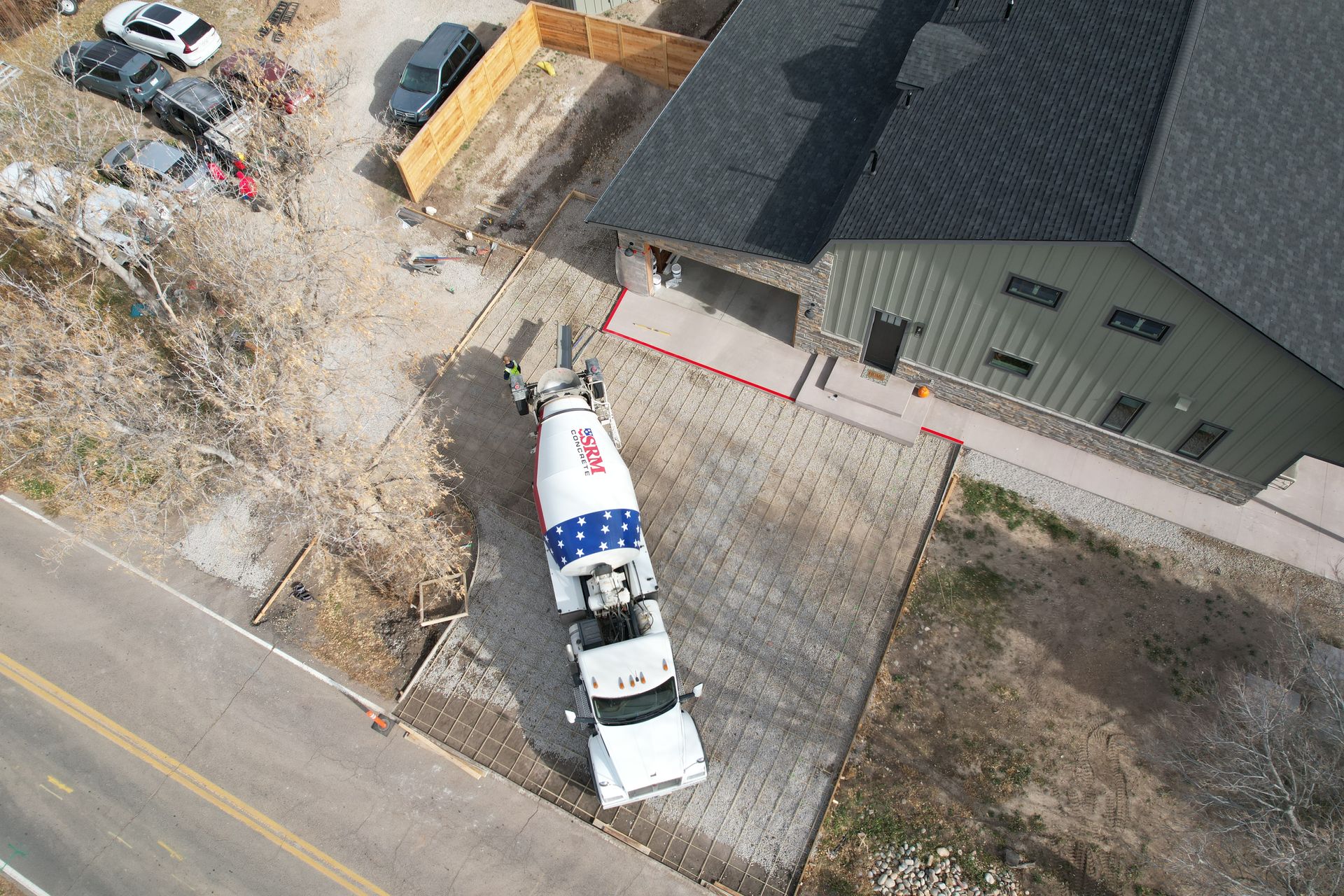 Aerial view of a white utility truck parked beside a house on a construction site.