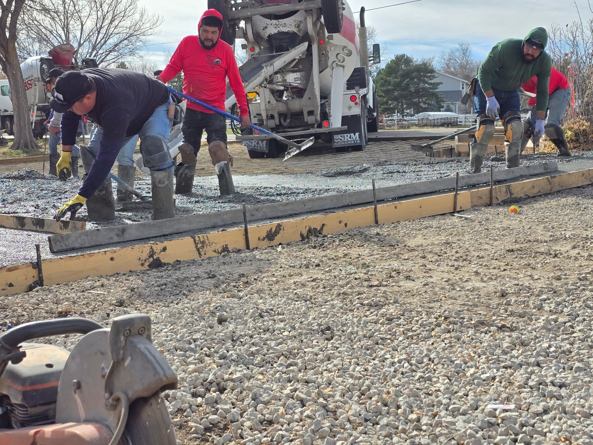 Construction workers leveling gravel for a curved curb at a roadwork site