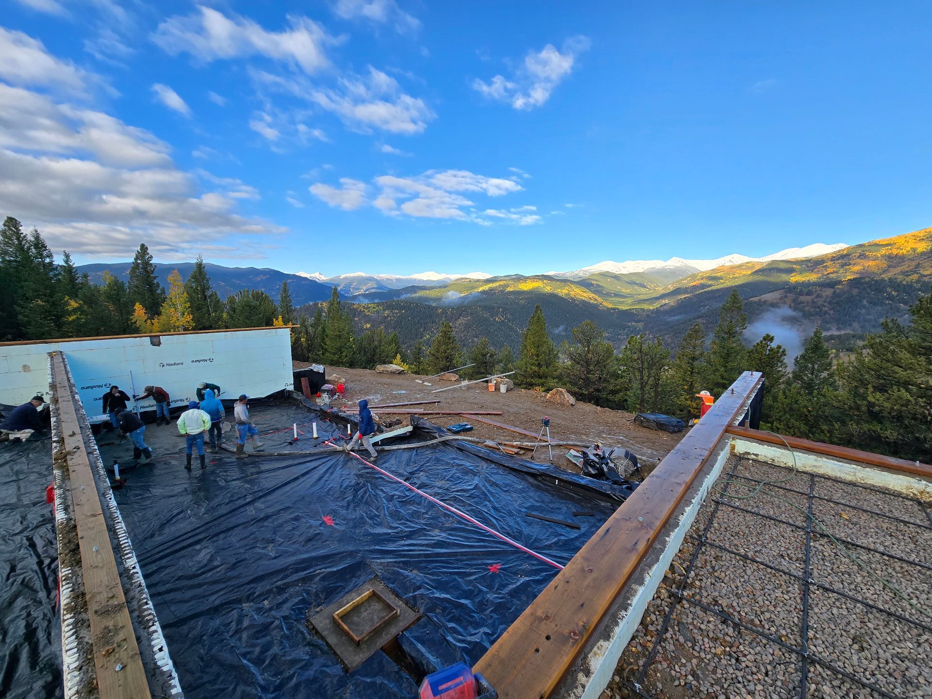 Workers on a rooftop under construction with a mountain view and blue sky at sunset