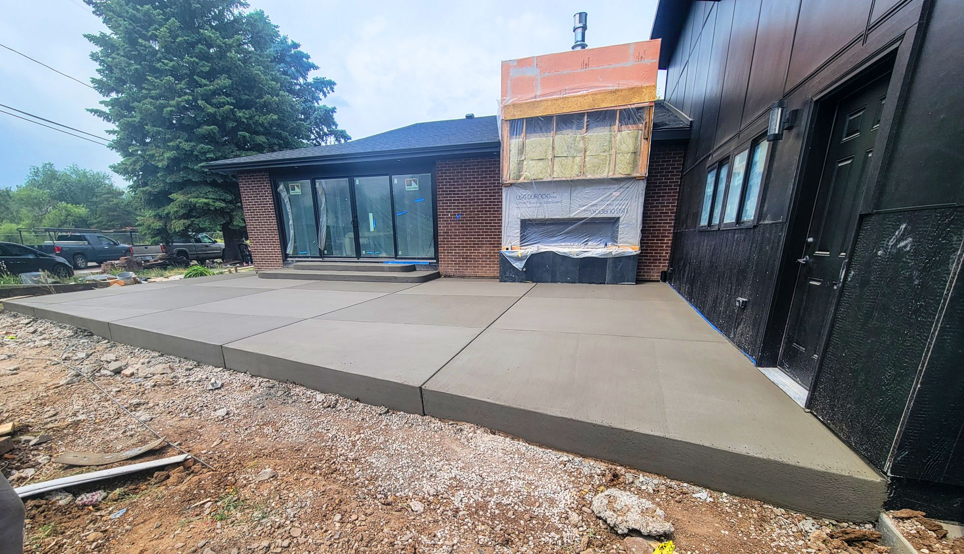 Concrete sidewalk ramp beside a brick-and-glass building entrance under construction