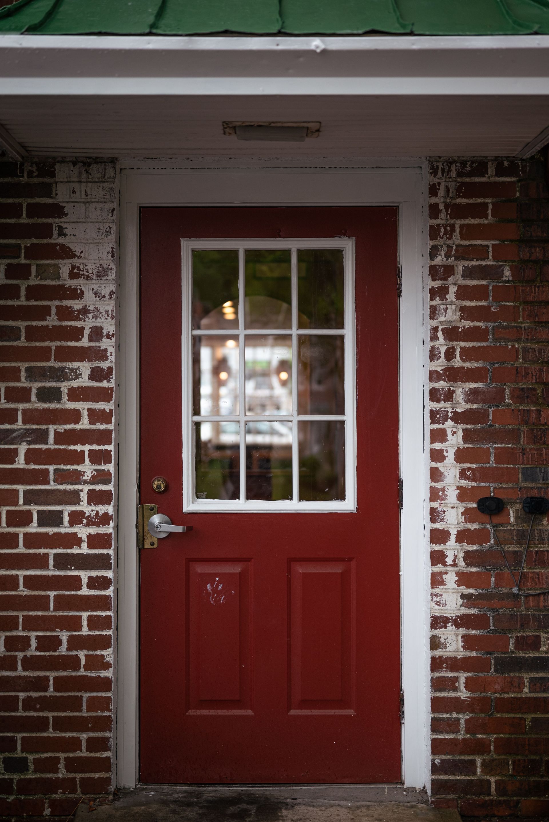 Close-up of a wooden door with a silver lever handle slightly ajar.