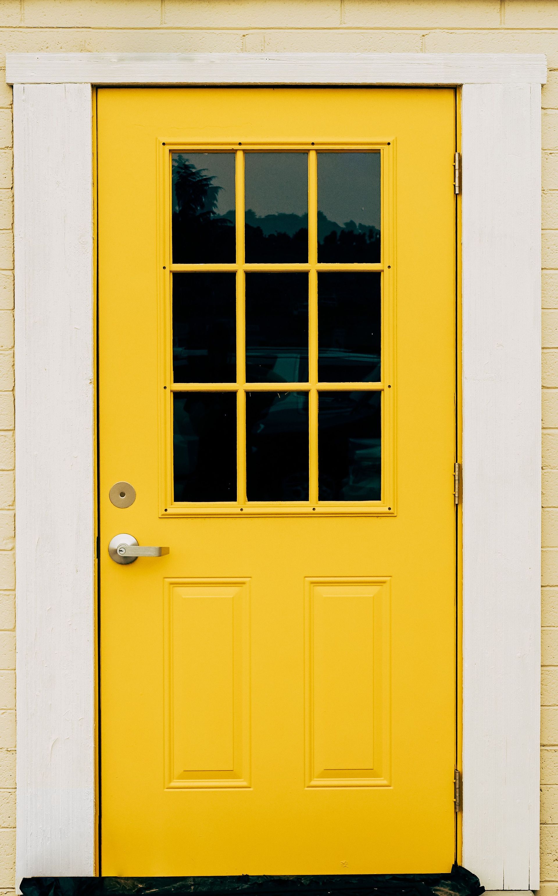 Black door handle and lock on a bright blue door.