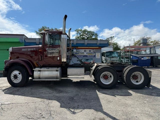Red semi-truck parked beside a blue building on a sunny street