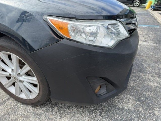 Front corner of a black car with headlight, wheel, and fog light visible.