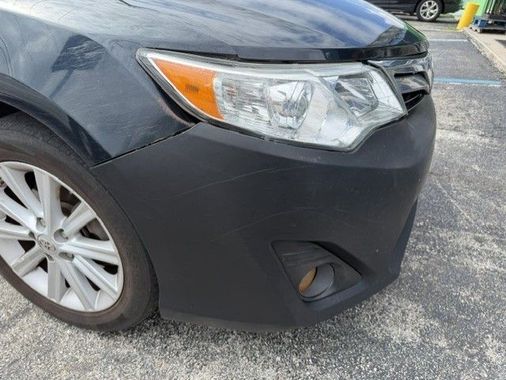 Front corner of a black car with headlight, wheel, and fog light visible.