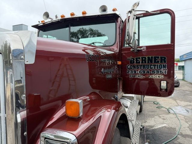 Red semi truck with open door parked at a construction site, bearing Berner Construction lettering