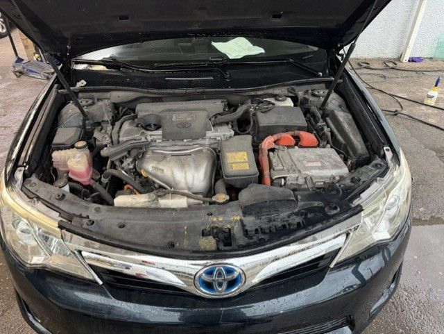 Open car hood showing a Toyota engine bay with the battery and engine components visible.