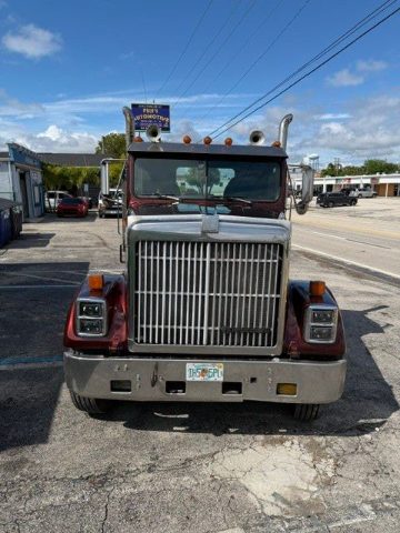 Red semi-truck parked on a roadside under a blue sky