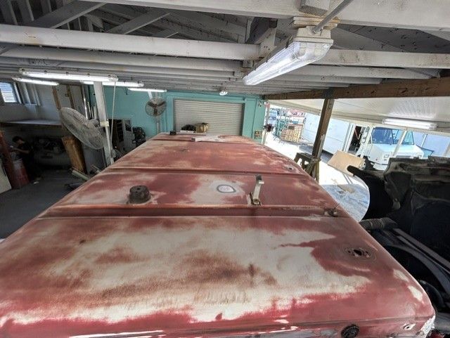 Rusted red vehicle roof inside a cluttered garage, viewed from above