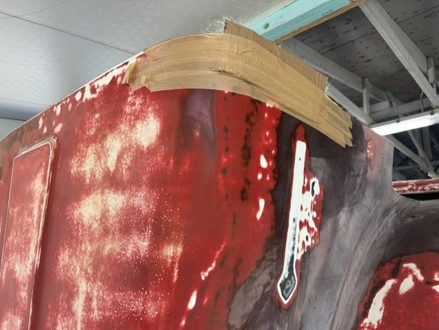 Red-painted giant statue head with a tan band across the top, shown indoors under a ceiling.