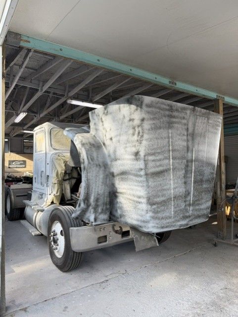 Truck carrying a large, shrink-wrapped load parked under a covered structure