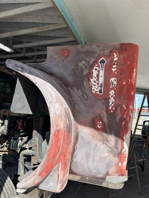 Rusty red truck front panel with large curved intake scoop under a roof