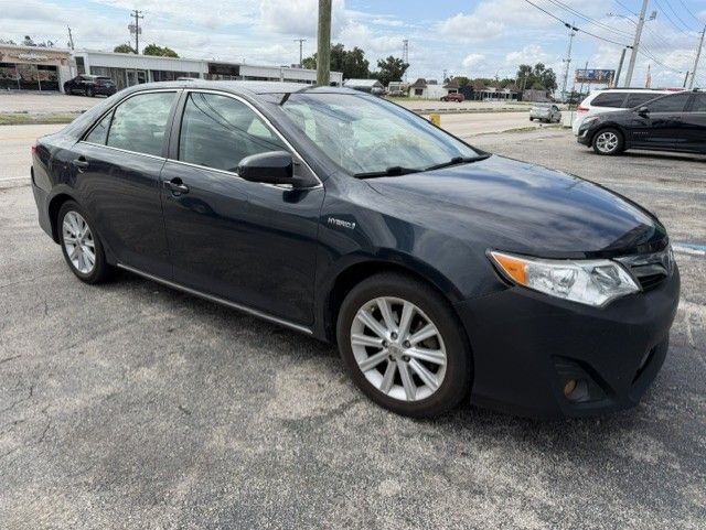 Dark gray sedan parked on a lot under a cloudy sky